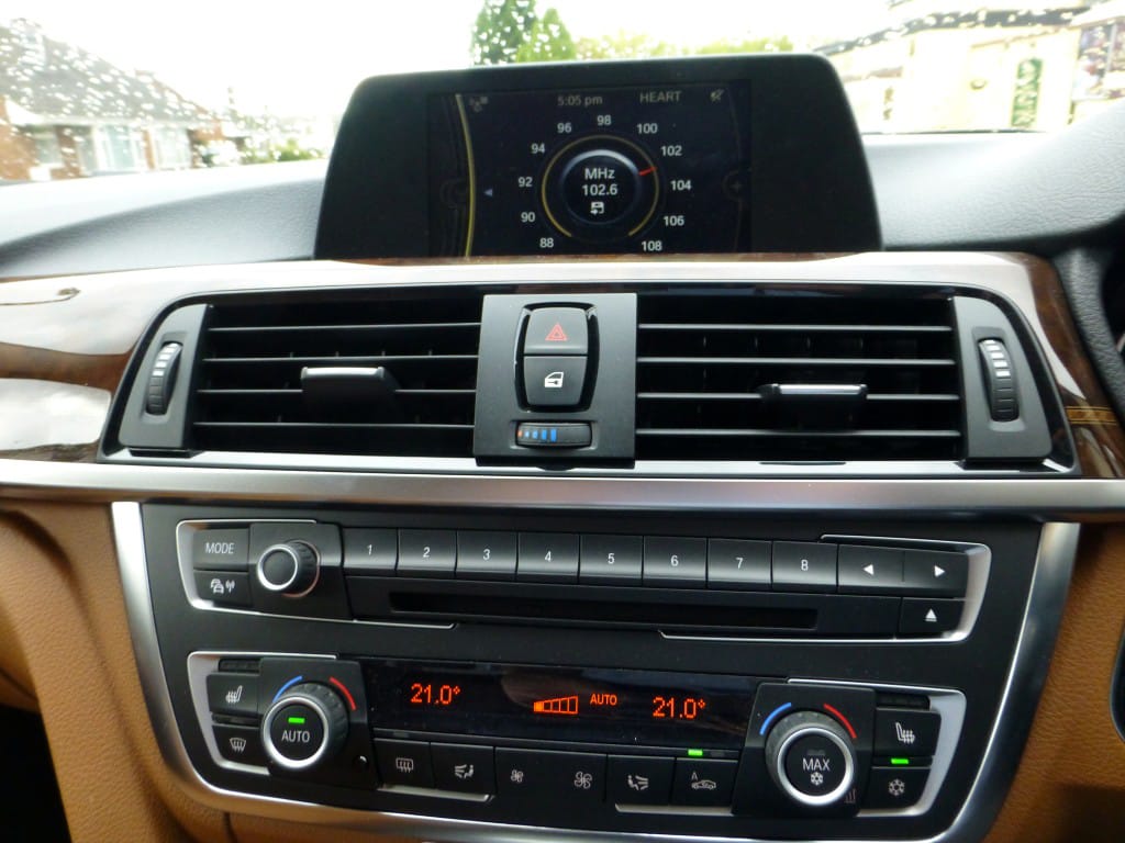 A BMW car's dashboard with air conditioning vents, a sound system, and a digital display screen
