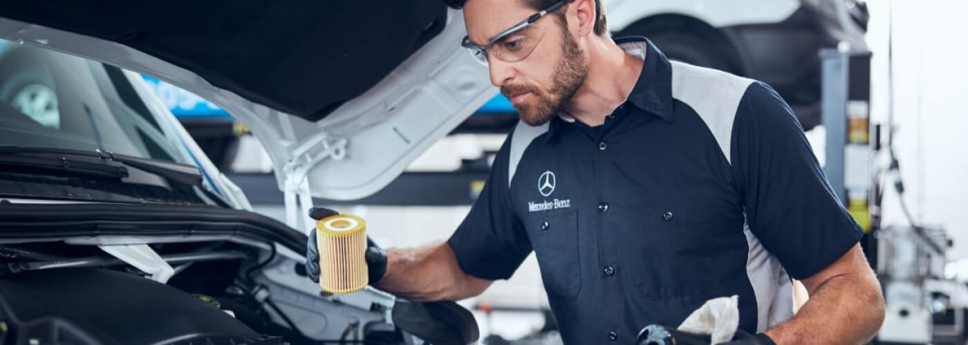 A mechanic is inspecting a Mercedes Benz car's oil