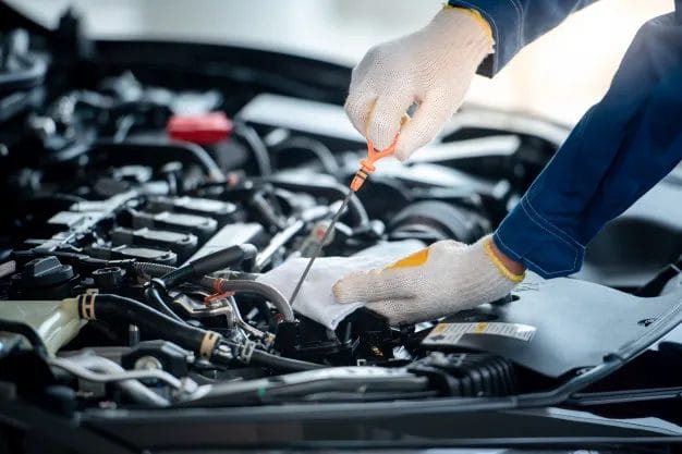 A mechanic is checking oil level of a car