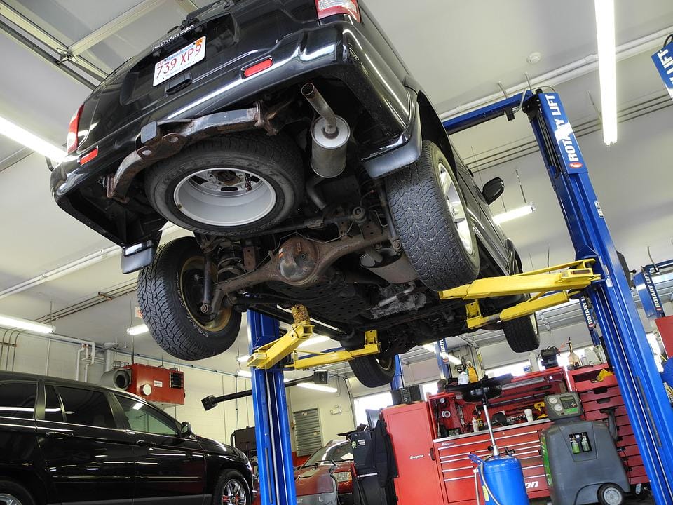 A car is uplifted on a car lift in a mechanic's shop