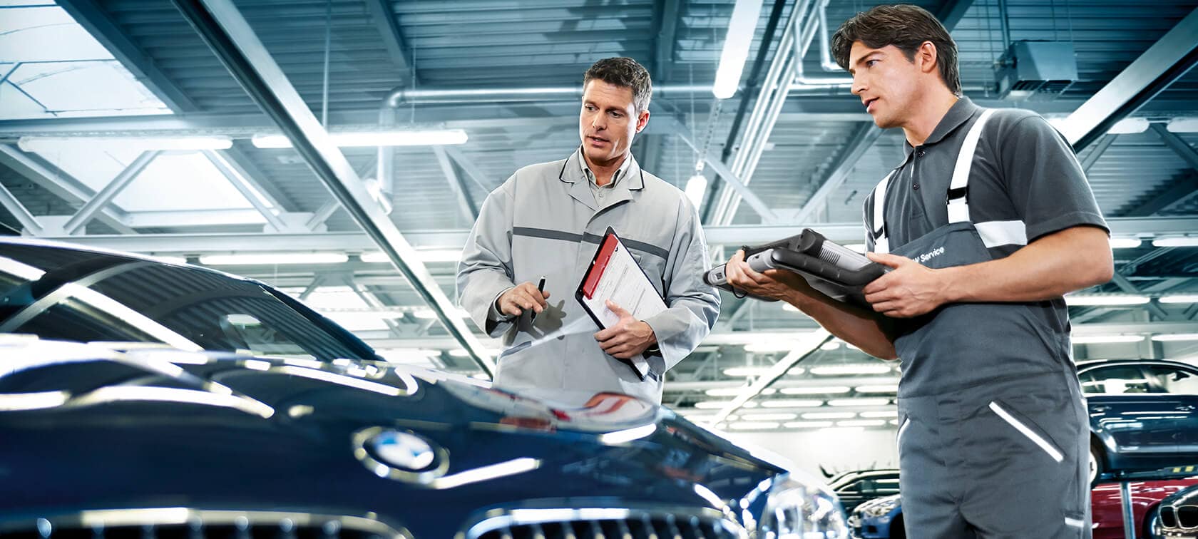 Two mechanic inspecting a BMW car in mechanic's shop