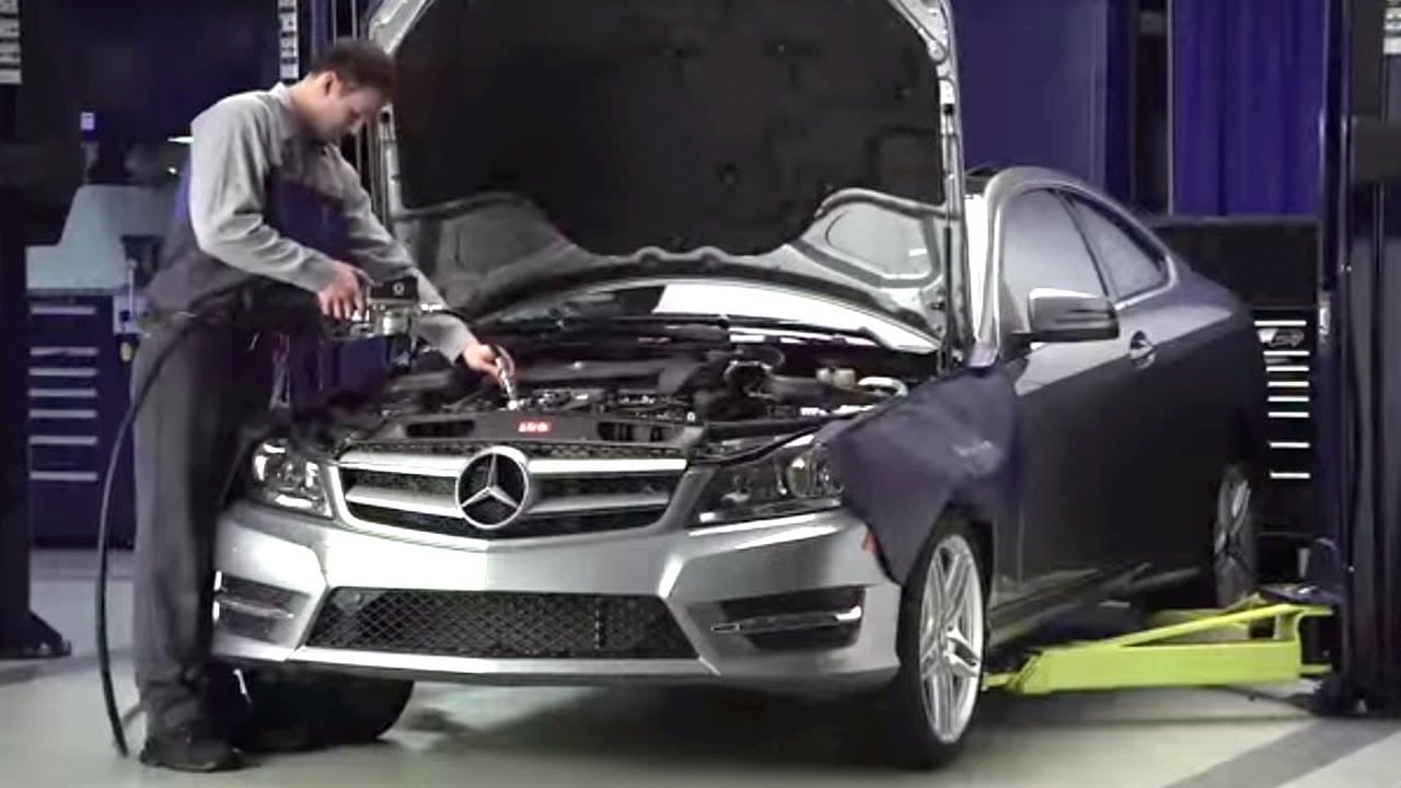 A mechanic is filling a fluid in a Mercedes Benz